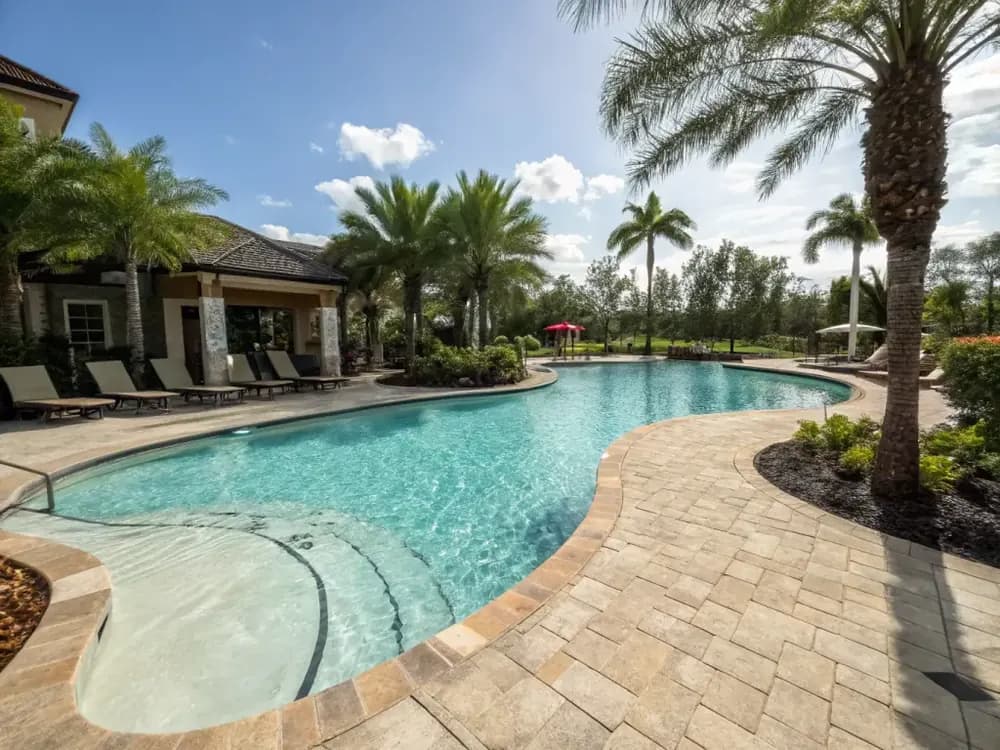 Luxury Florida swimming pool with resurfaced pool deck in warm sand tones surrounded by tropical landscaping