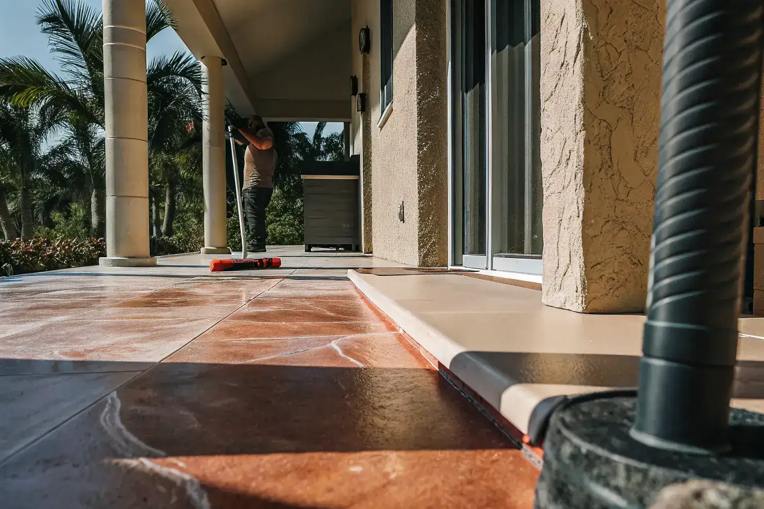 Professional decorative concrete resurfacing being applied to a Florida patio with palm trees in the background