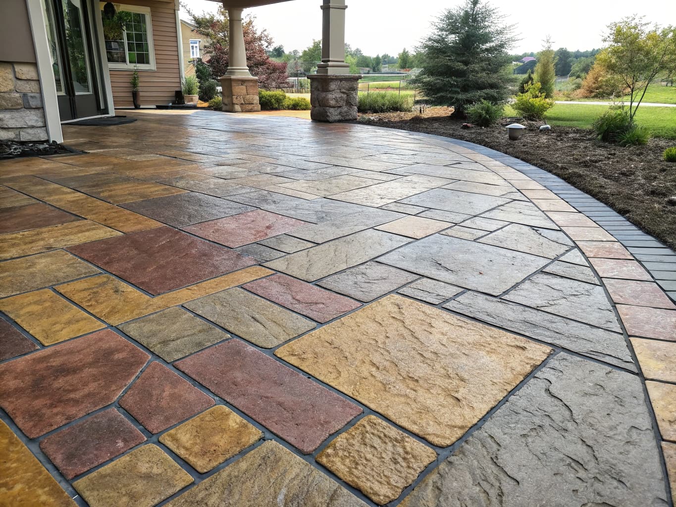 Multi-tone stamped concrete patio with layered amber, beige, and gray color blending mimicking natural flagstone