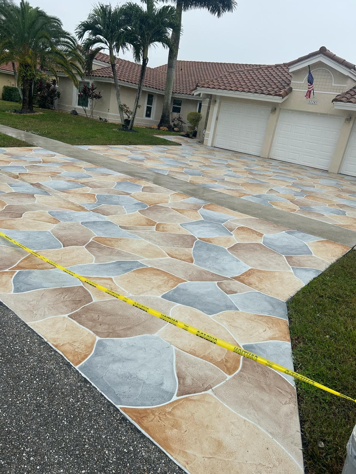 Multi-tone flagstone stamped concrete driveway with warm gold, gray, and tan color blending on a Florida home