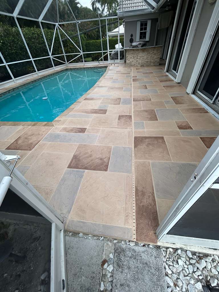 Multi-tone stamped concrete pool deck with layered beige, brown, and gray color blending surrounding a Florida swimming pool