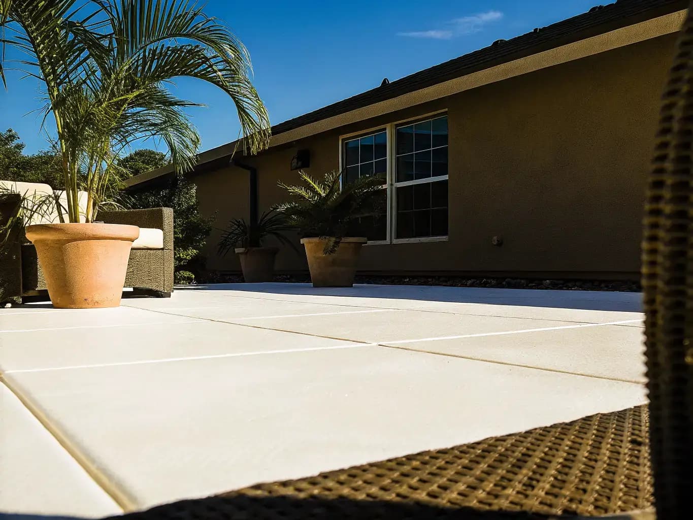 Florida backyard patio with freshly resurfaced concrete overlay, potted plants, and outdoor wicker furniture