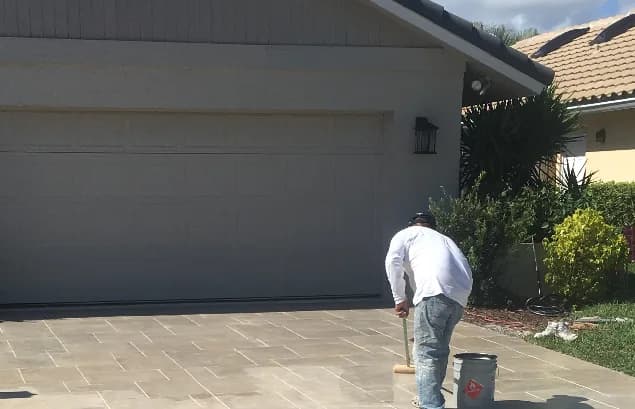 Concrete Magic crew member applying concrete overlay coating to a Florida driveway surface