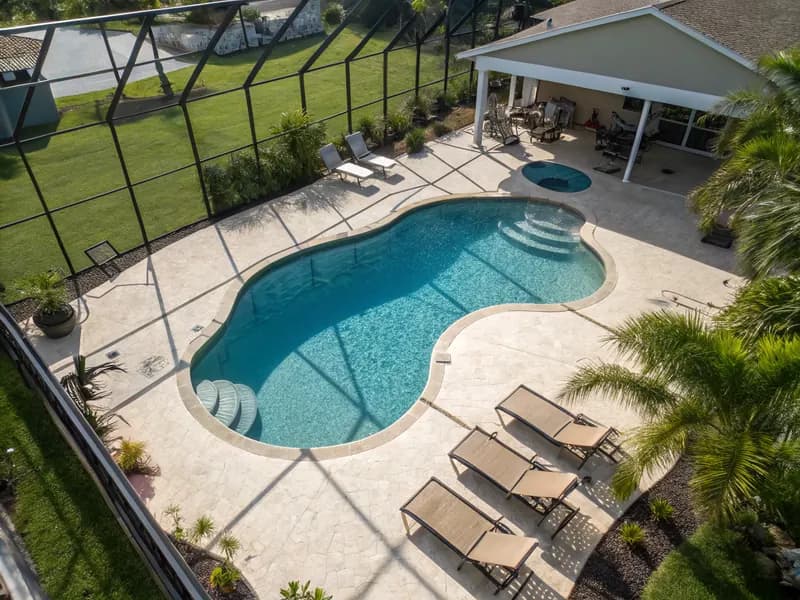 Aerial view of a Florida pool deck with freshly applied SprayDeck coating surrounding a sparkling swimming pool with lounge chairs