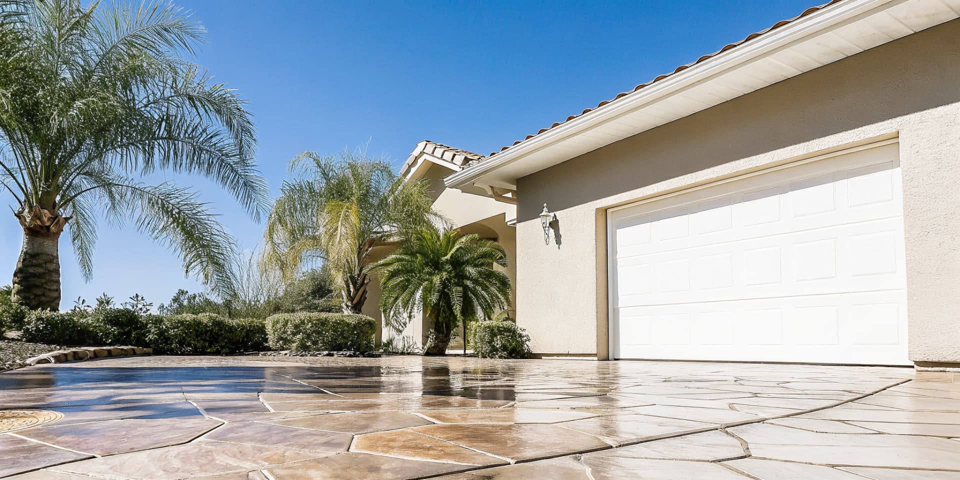 Professionally installed stamped concrete driveway in pristine condition showing multi-tone flagstone pattern with perfect joints and no degradation