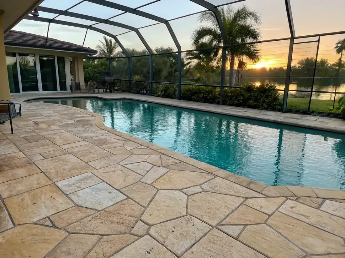 Multi-tone beige flagstone pattern with natural stone appearance surrounding screened pool