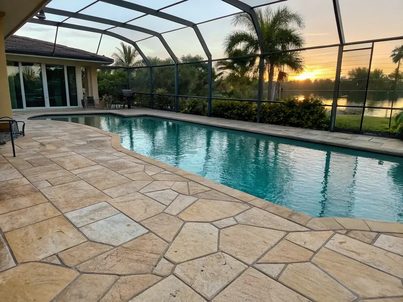 Multi-tone beige flagstone pattern with natural stone appearance surrounding screened pool