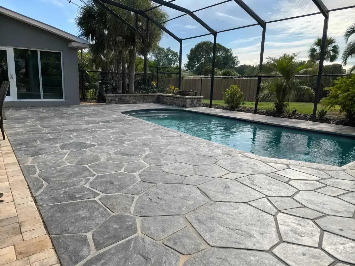 Cool-tone gray flagstone stamped concrete pool deck under screened enclosure