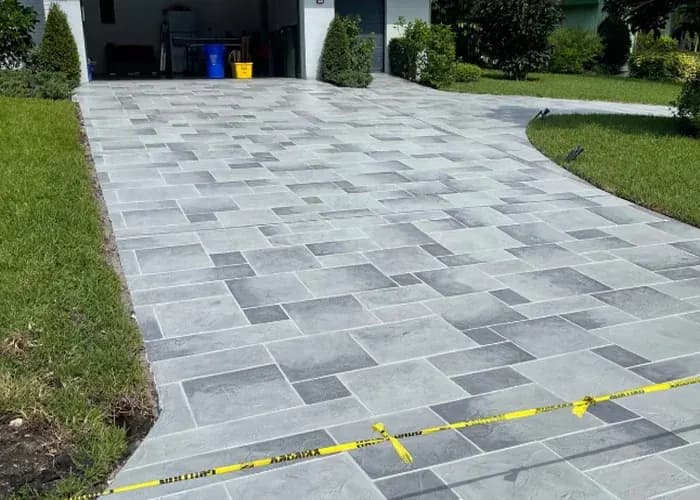 Newly installed gray paver driveway with landscaped front yard in Naples FL